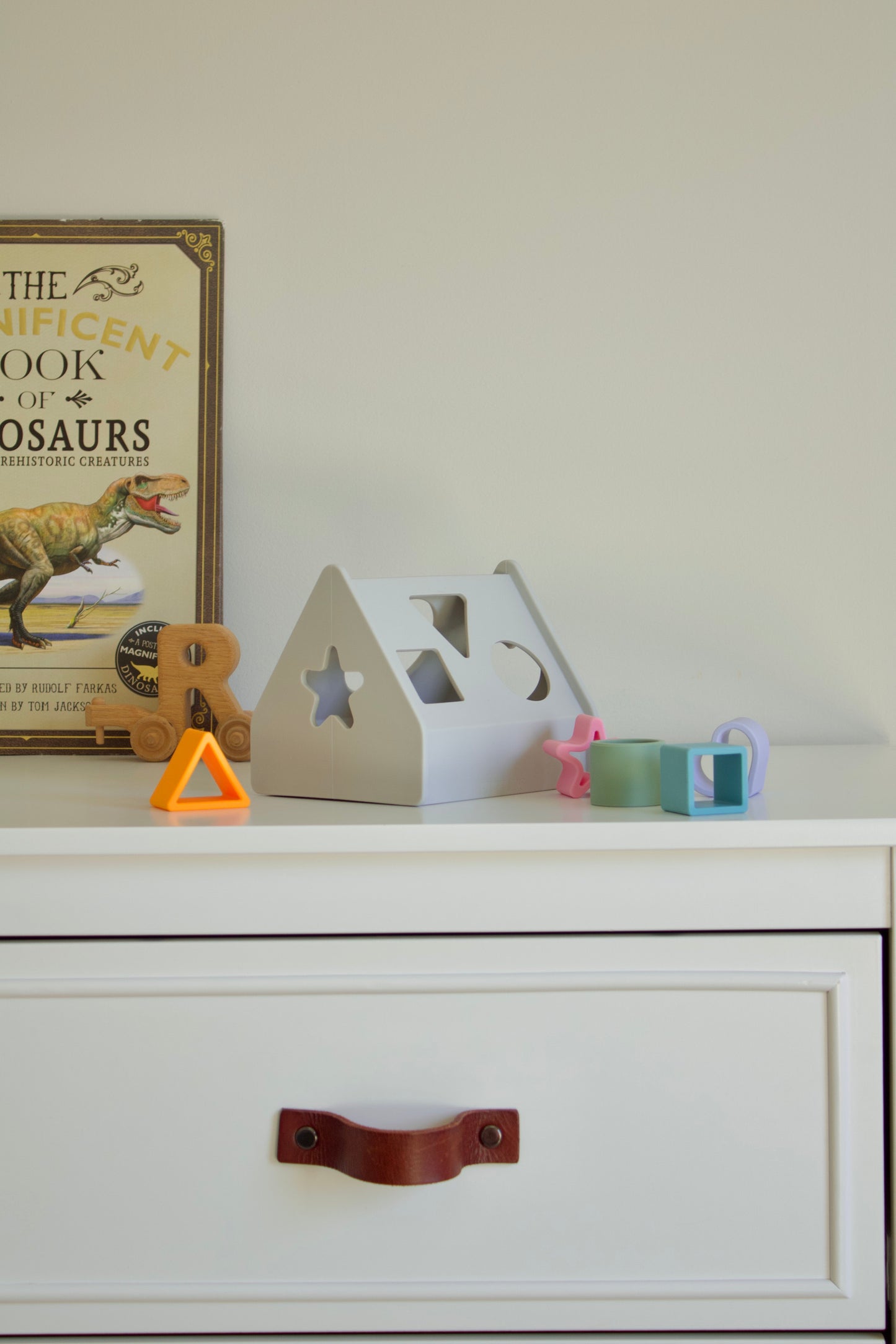 Puffling the sorting house, shape sorting toy, shape sorter toy, developmental toddler toy, silicone nontoxic toy, developmental baby toy, learning toy, neutral baby toy, neutral toddler toy, mushie toy, mushie shape sorter, baby nursery decor view, sitting on dresser