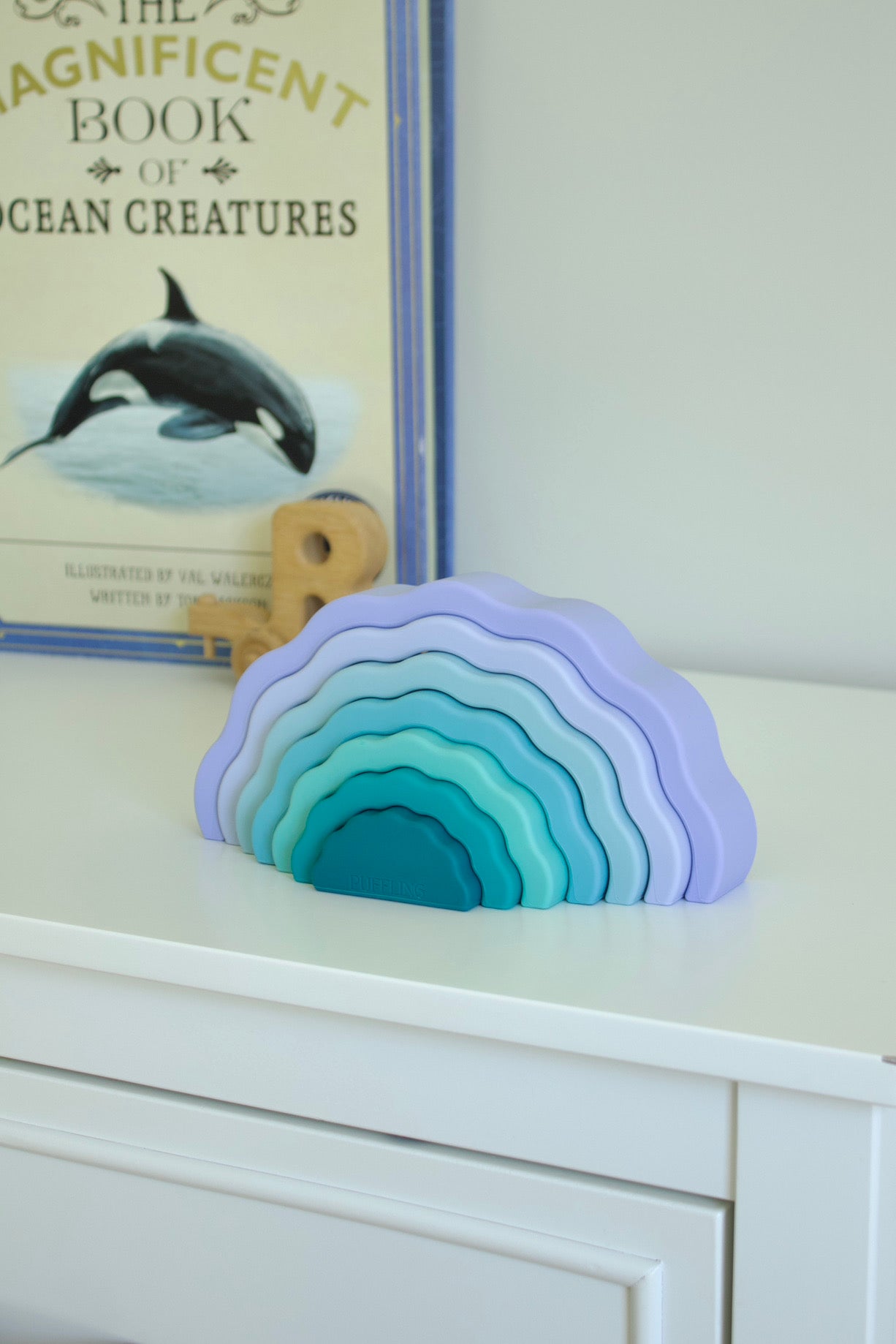 Puffling the Sunset Stacker, rainbow stacker toy, rainbow stacking toy, developmental toy, silicone toddler baby toy, nontoxic toy, wavy rainbow toy, glacier blue color, cocovillage, mushie toy, view on dresser